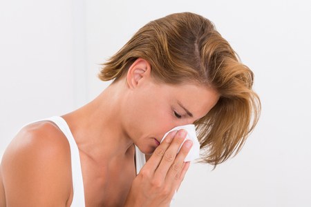 sick woman blowing nose